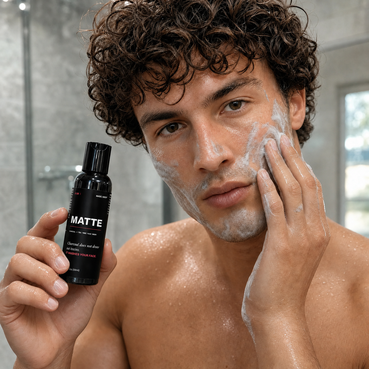 MASC/BODY MATTE charcoal + tea tree face wash — model mid-wash holding the bottle