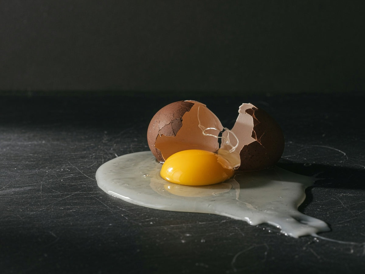 A cracked brown egg, the yolk whole and glossy gold.
