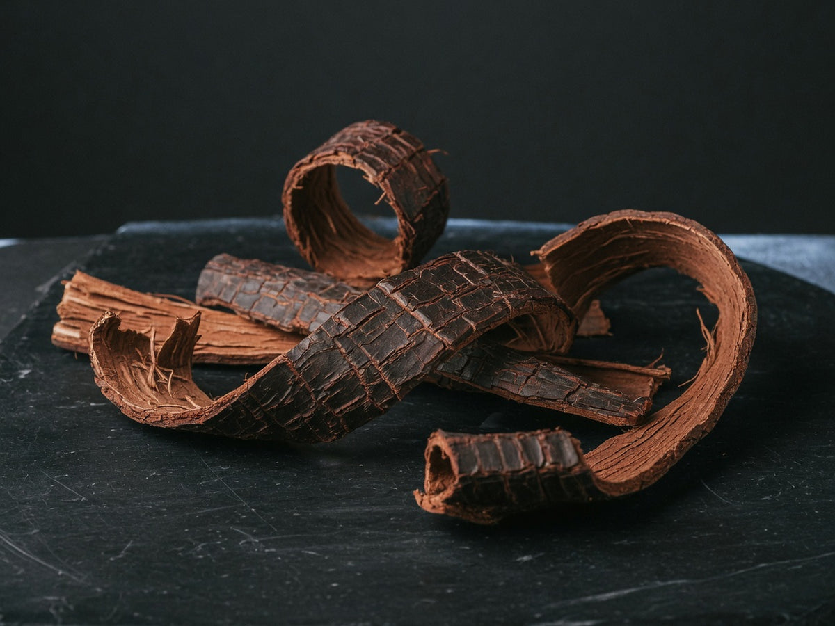 Curled strips of reddish-brown catuaba bark overlapping on black stone.