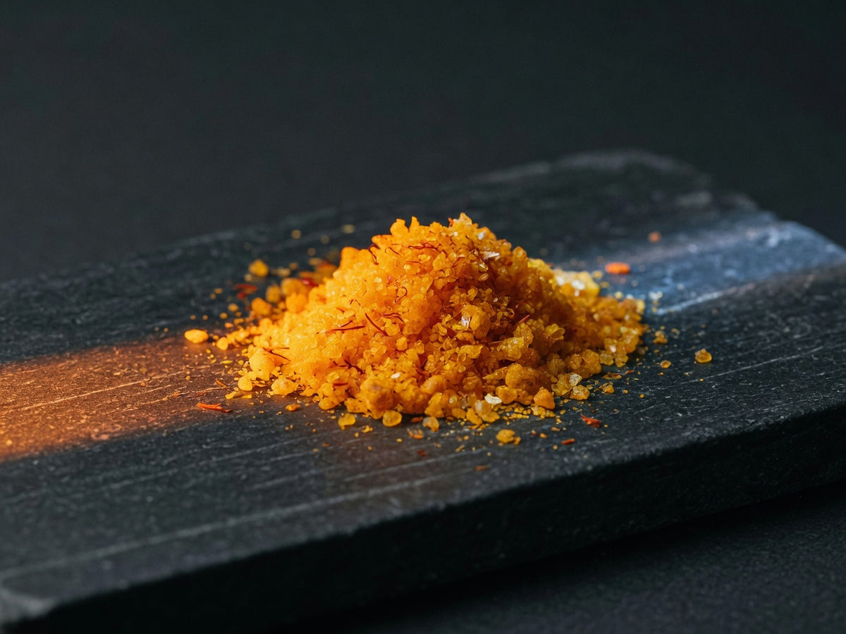A glowing mound of vivid orange-yellow CoQ10 crystalline powder.