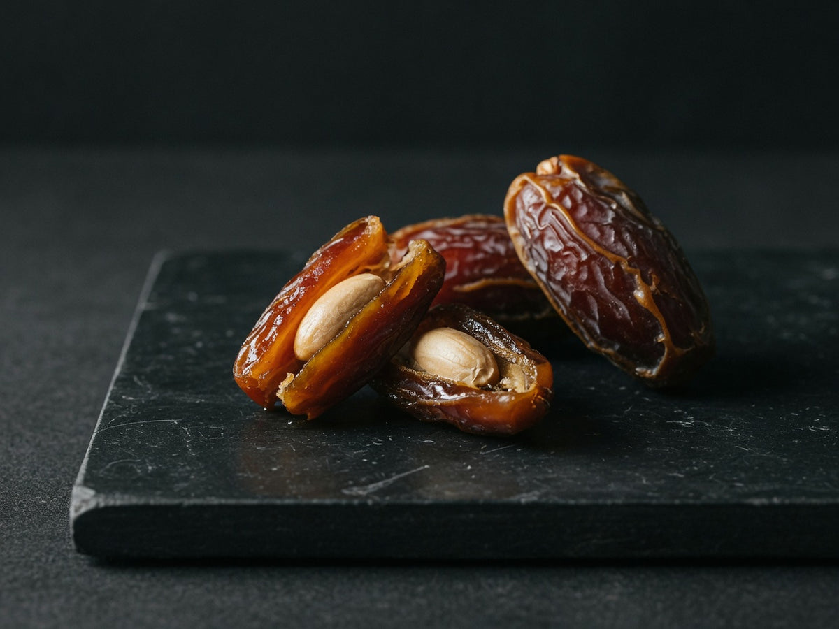 Wrinkled brown dates, split open to show their smooth pale stones.