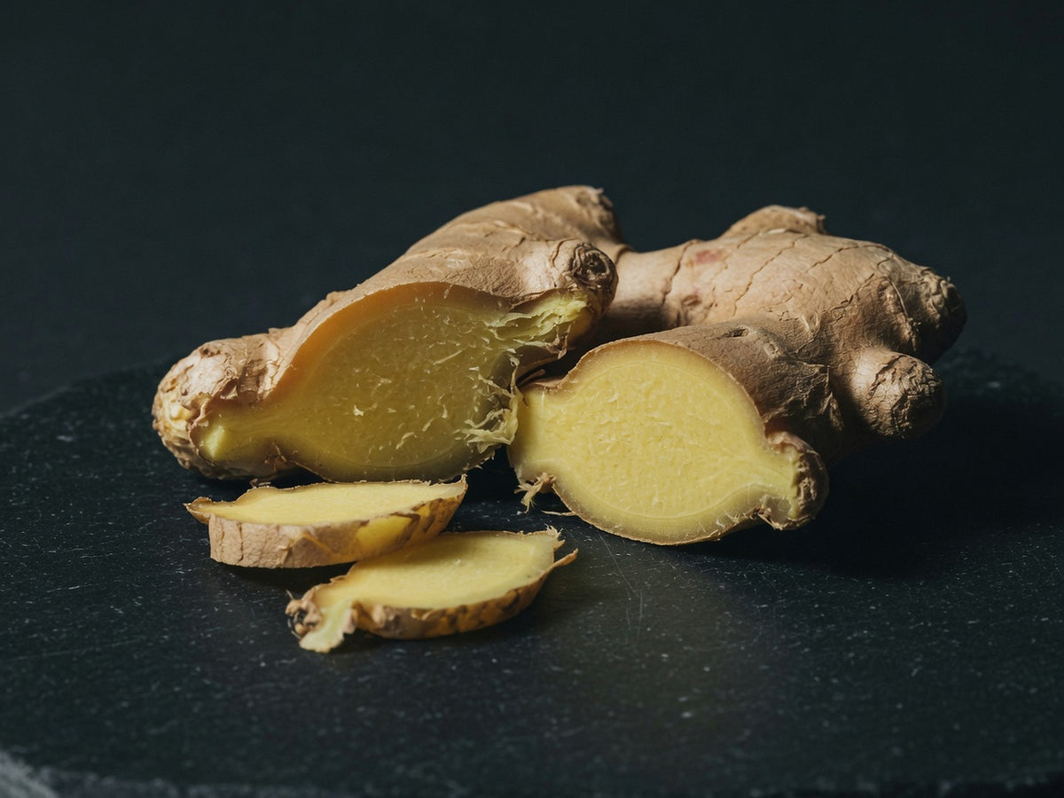 Fresh ginger rhizome split to show pale fibrous interior against knobby tan skin.