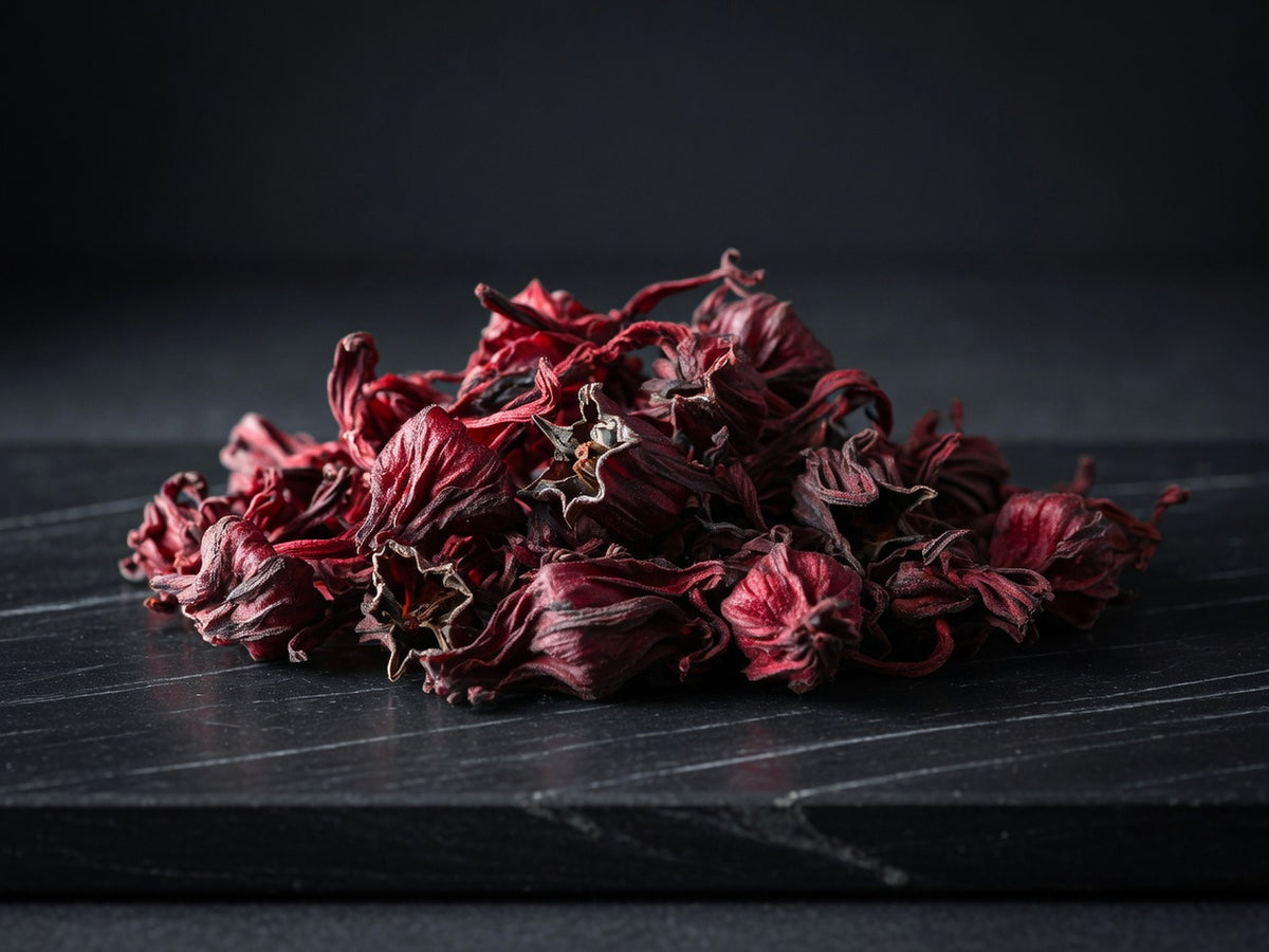 A heap of dried hibiscus calyces, deep crimson and curled.