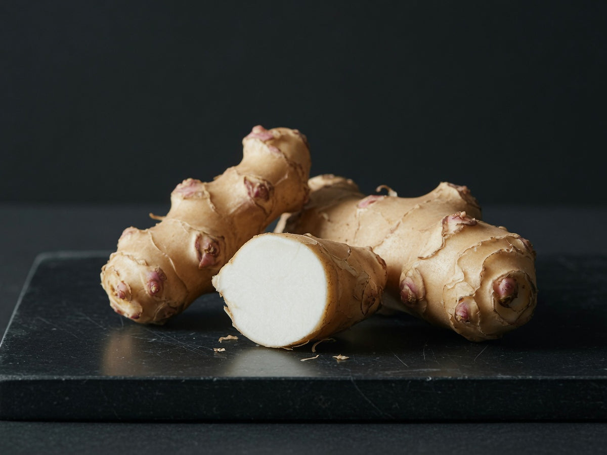 Knobbly beige Jerusalem artichoke tubers, one cut to show white flesh.