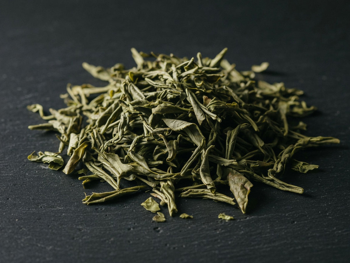 A sculptural heap of twisted olive-green loose tea leaves.