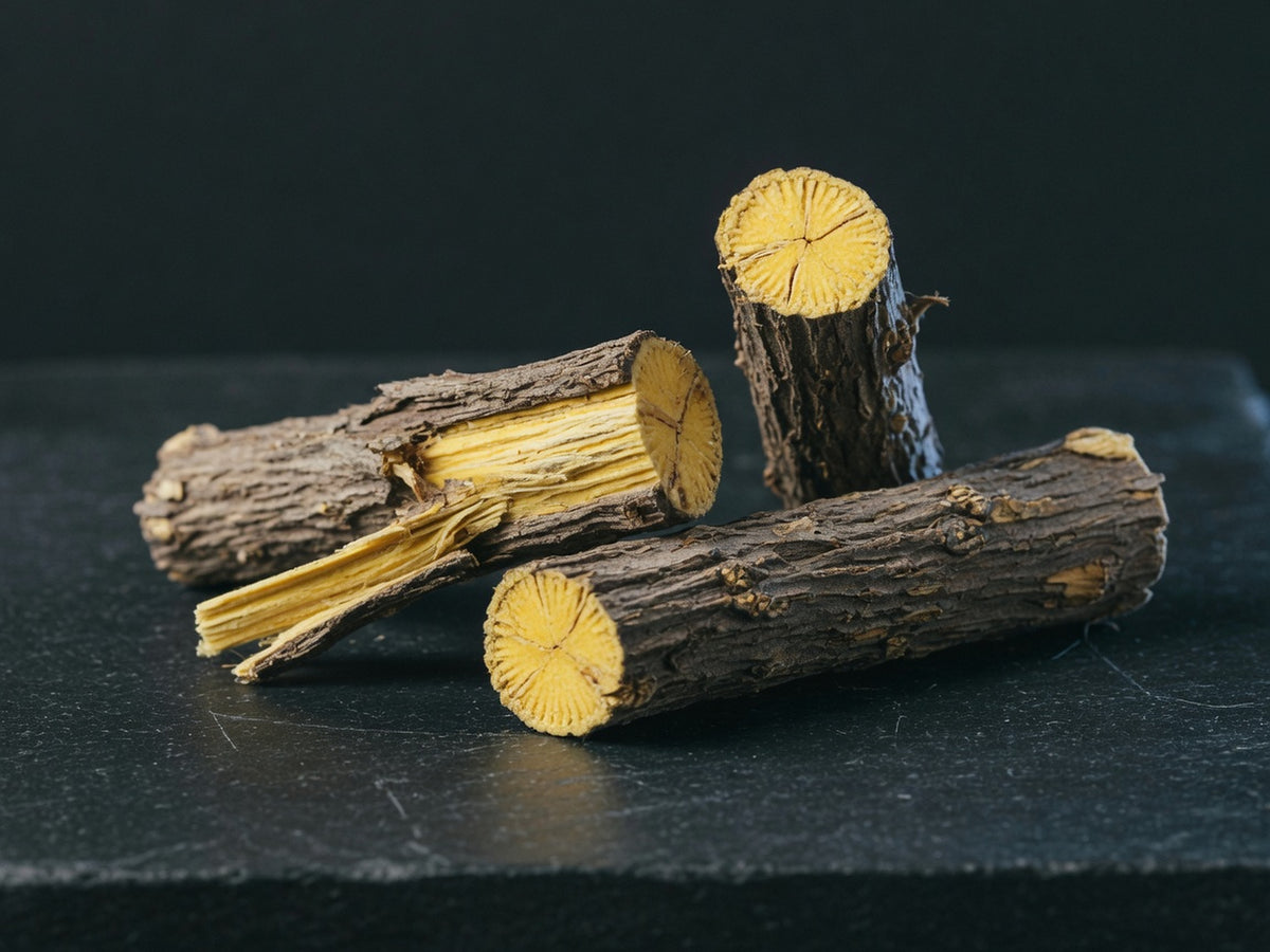 Cut lengths of woody licorice root, grey bark outside and a bright fibrous yellow core at the cut ends.