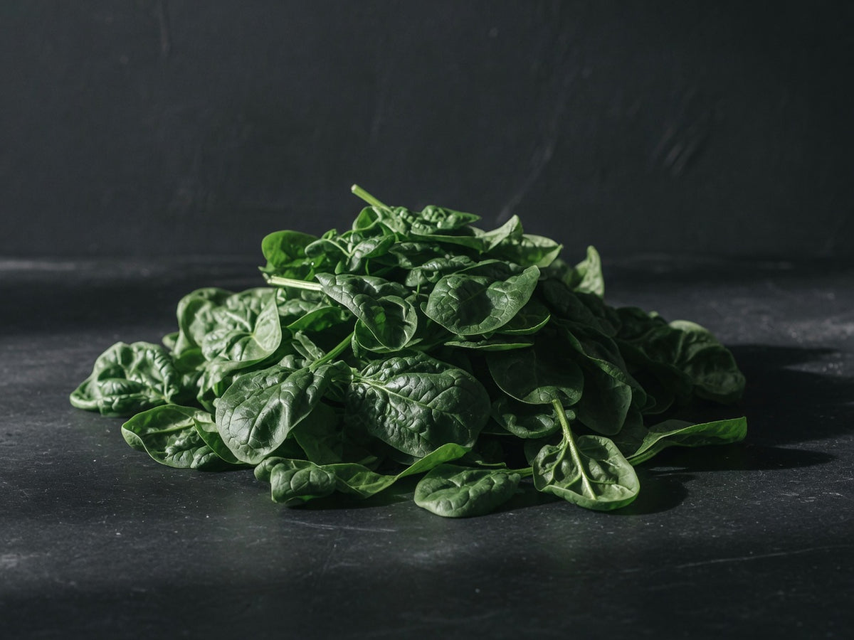 A loose sculptural pile of dark green spinach leaves with visible veins.