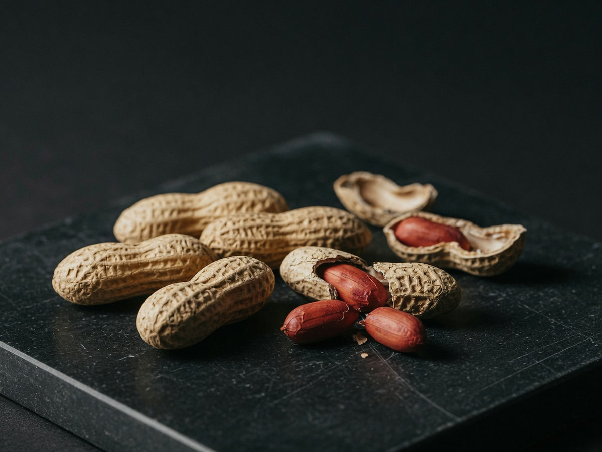Peanuts in their ridged tan shells, one broken open with red-skinned kernels spilling out.
