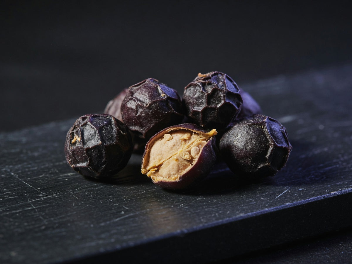 Dark purple-black dried saw palmetto berries, wrinkled, one split open.