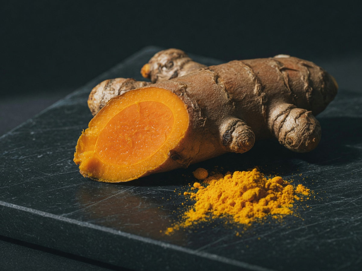 Cut turmeric rhizome showing brilliant orange interior, with a pile of yellow powder.