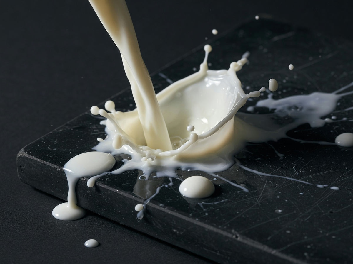 A pour of whole milk frozen mid-splash, with thick droplets.