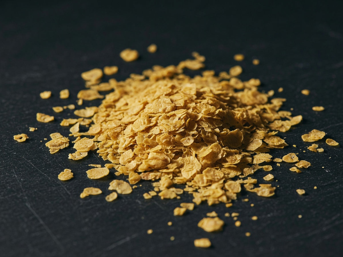 A loose heap of golden-yellow nutritional yeast flakes.